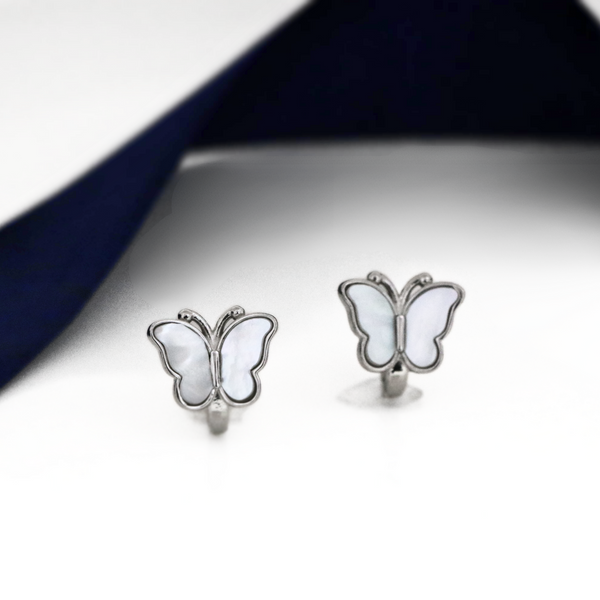 A pair of silver butterfly-shaped earrings with translucent light blue wings, displayed on a white surface with a navy blue background.