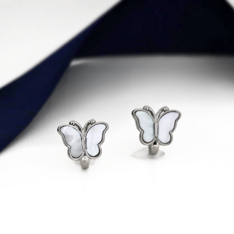 A pair of silver butterfly-shaped earrings with translucent light blue wings, displayed on a white surface with a navy blue background.